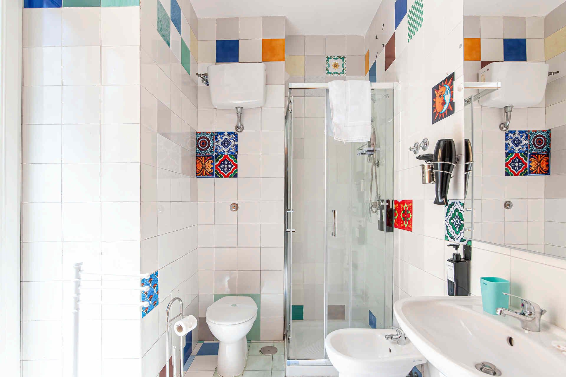 Une salle de bain avec une douche à parois de verre, des toilettes et un lavabo.
