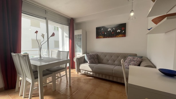 A modern living room with a dining area, a sofa, and a painting on the wall.