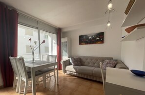 A modern living room with a dining area, a sofa, and a painting on the wall. - Apartamento Aurora 3 by Mallorca North Villas (Port de Pollença)