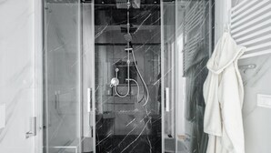 Une salle de bain moderne avec une douche à parois de verre, une serviette blanche accrochée au mur et un sol en marbre.