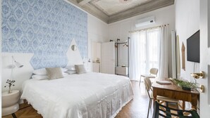 Une chambre à coucher avec un grand lit, un bureau en bois, une chaise, un miroir et un téléviseur.