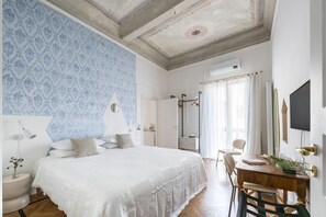 Ein Schlafzimmer mit einem großen Bett, einem Holztisch, einem Stuhl, einem Spiegel und einem Fernseher.