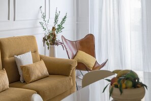 Un salon avec un canapé, un fauteuil en cuir et un vase rempli de fleurs.