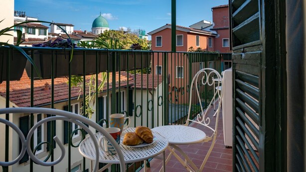Un balcon avec une table, des chaises et une vue sur des immeubles et un dôme en arrière-plan.