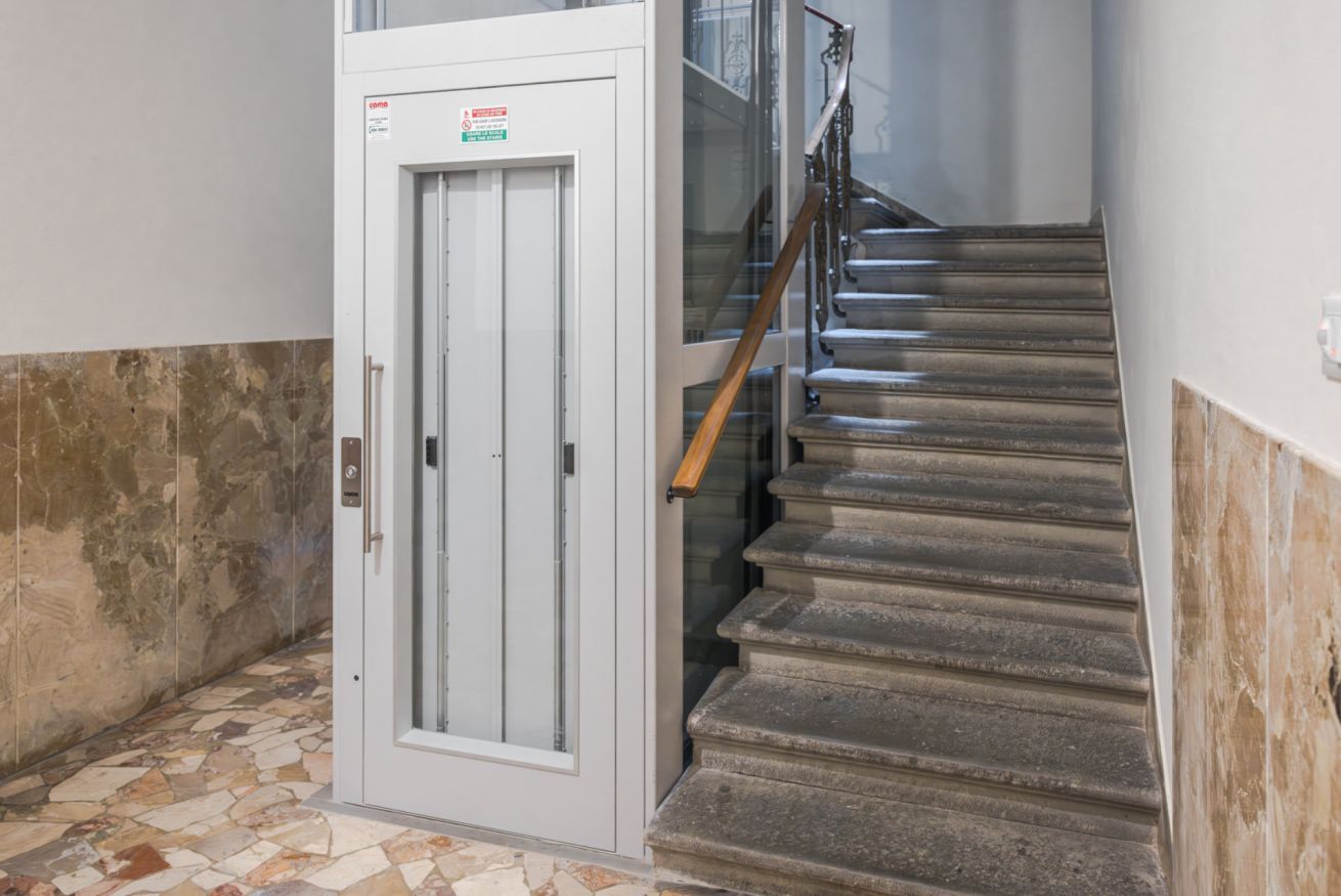 A staircase with a handrail, a door with a safety sign, and a tiled floor.