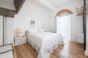 Une chambre à coucher comprenant un lit, une table de chevet, une lampe et une porte donnant sur une autre pièce.