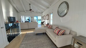 Un salón amplio con un sofá grande, un tapete estampado y vistas al exterior.