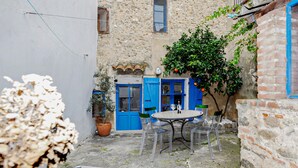 Ein Innenhof mit einer blauen Tür, einem Tisch mit Stühlen und einem Blumentopf.