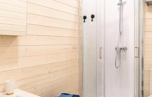 Bathroom features a glass-enclosed shower with handheld showerhead and faucet.
