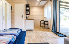 Cozy retreat with a neatly made bed, compact kitchenette, and dining area.