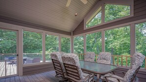 A covered deck with a table and chairs, large windows, and a view of trees. - Expansive 5b6ba Countryside Home in welcoming Galena (Galena)