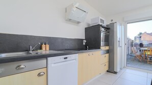 A modern kitchen with a dishwasher, a microwave, and a built-in oven. There is a sliding glass door leading to an outdoor area with a table and chairs. - 4 bedroom gorgeous home in Petite-Synthe (Petite-Synthe)
