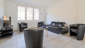 A modern living room with a sofa, two armchairs, a coffee table, and a television. - 4 bedroom gorgeous home in Petite-Synthe (Petite-Synthe)