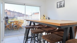 A modern kitchen with a wooden bar and stools, a large window, and a view of the neighborhood. - 4 bedroom gorgeous home in Petite-Synthe (Petite-Synthe)