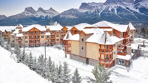 Un chalet enneigé doté de plusieurs balcons, avec une vue sur les montagnes en toile de fond.