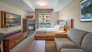 Une chambre à coucher moderne avec une cheminée, un grand lit, un canapé et un téléviseur.