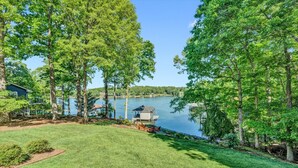 A lakeside property with a dock, a covered boat house, and a grassy lawn. - Pine and Paddle - Firepit / Water Toys / Gentle Lot / Foosball / Ping-Pong (Moneta)