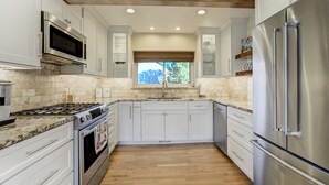 A modern kitchen with white cabinets, stainless steel appliances, and a wooden floor. - Hot Tub, Fire Pit, Bocce Ball+ (Colorado Springs)