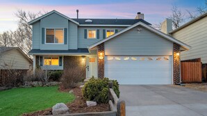 A two-story house with a garage, a well-maintained lawn, and a wooden fence. - Hot Tub, Fire Pit, Bocce Ball+ (Colorado Springs)