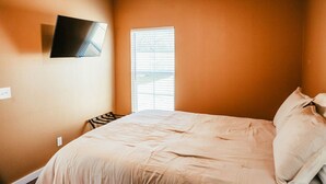 Una camera da letto con un letto, una ventola a soffitto, una TV montata a parete e una finestra con persiane.