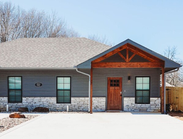 A two-story house with a stone foundation, a wooden front door, and a number '231' sign. - New 2 BR, 2B, 231 11th. NE unit2 (Paris)