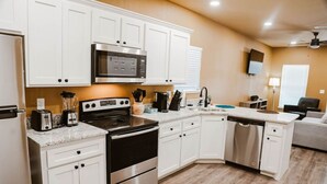A modern kitchen with white cabinets, stainless steel appliances, and a granite countertop.