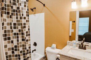 A bathroom with a shower curtain, toilet, sink, and a mirror. - New 2 BR, 2B, 231 11th. NE unit2 (Paris)