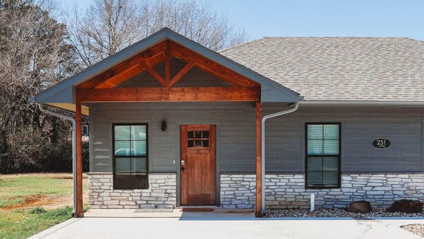 A two-story house with a stone foundation, a wooden front door, and two windows. - New, 2 BR, 2B,  231 11th NE, #1 (Paris)