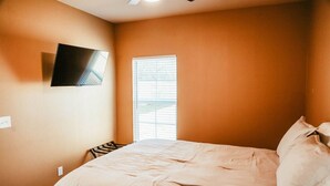 A bedroom with a bed, a TV mounted on the wall, and a window with blinds. - New, 2 BR, 2B,  231 11th NE, #1 (Paris)