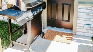 An outdoor grill setup in front of a house with a door and a window. - New, 2 BR, 2B,  231 11th NE, #1 (Paris)