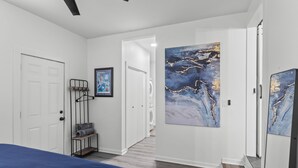 A bedroom with a bed, a wardrobe, a hanging rack, and a large abstract painting on the wall. - Spacious 4-bedroom Modern Bungalow in Charlotte! (Charlotte)