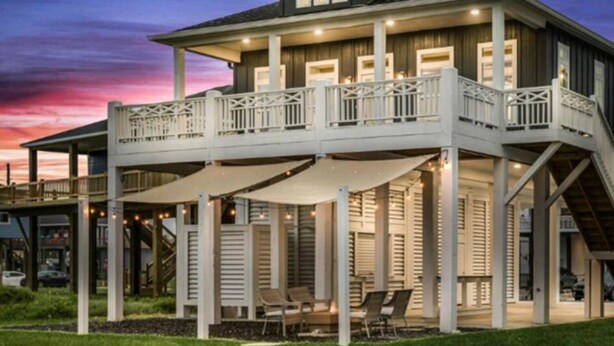 A two-story house with a balcony, outdoor seating, and a covered patio area. - Perfect Beach Getaway Home!  Beautiful property! (Bolivar Peninsula)