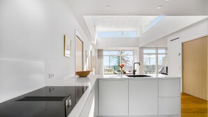 A modern kitchen with a black countertop, white cabinets, and a skylight.