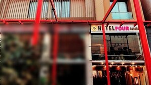 A multi-story hotel with a modern facade, featuring horizontal lines and a prominent entrance with a sign reading "HOTEL FOUR". - Hotel Four Square  (Karachi)