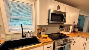 Une cuisine moderne avec des armoires blanches, un four à micro-ondes en acier inoxydable, une cuisinière et un évier.