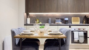 Una cocina moderna con una mesa de comedor dispuesta para dos personas, equipada con cafetera, tostadora y tetera.