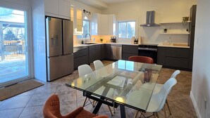Een moderne keuken met een glazen eettafel, oranje stoelen en een inbouwoven.