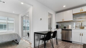A modern kitchen with white cabinets, a stainless steel dishwasher, and a marble backsplash. - Modern Stylish Oasis in Downtown Dallas w Parking (Dallas)