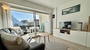 A modern living room with a sofa, TV, and a small table. - Quiberon - 2rooms - 27m² - beach (QUIBERON)