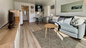 A modern living room with a grey sofa, a small wooden coffee table, and a patterned rug. - Quiberon - 2rooms - 27m² - beach (QUIBERON)