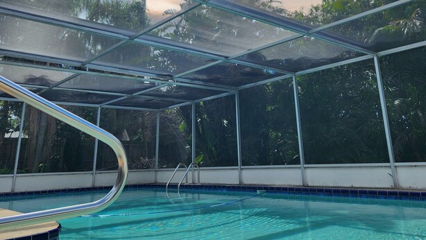 An indoor swimming pool with clear water, surrounded by a glass enclosure, and palm trees visible outside. - Free Huge Heated Pool, Spacious, Comfy Beachy Vibes! (Largo)