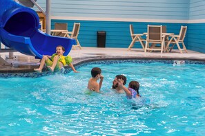 A pool area with a blue slide, lounge chairs, and a tiled pool edge. - Cabin with Pond View, Private Hot Tub, Indoor Pools & Free Attraction Tickets (Hollister)