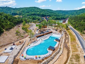 A resort with a large swimming pool, lounge areas, and a view of the surrounding forested hills. - Cabin with Pond View, Private Hot Tub, Indoor Pools & Free Attraction Tickets (Hollister)