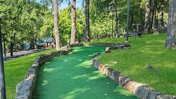 Ein Golfplatz mit künstlichem Rasen, Steinrändern und Bäumen im Hintergrund.