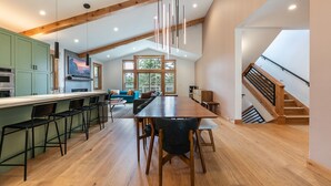A spacious kitchen with a long island, wooden beams, and a modern pendant light.