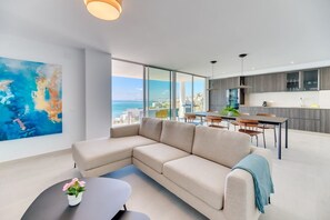 A modern living room with a large sectional sofa, a dining area with a table and chairs, and a kitchen with a view of the sea. - Navio | Sea view - pool - terrace (Benalmádena)