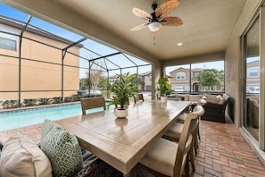 A covered patio with a pool, outdoor seating, and a ceiling fan.