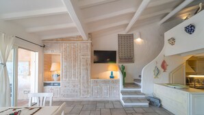 A kitchen with white cabinetry, a dining table, and a staircase leading to an upper level.