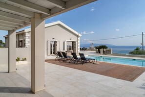 En modern byggnad med pool, utomhusmöbler och utsikt över havet.