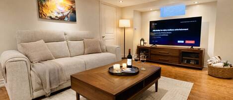 A modern living room with a sofa, coffee table, TV, and a painting on the wall.